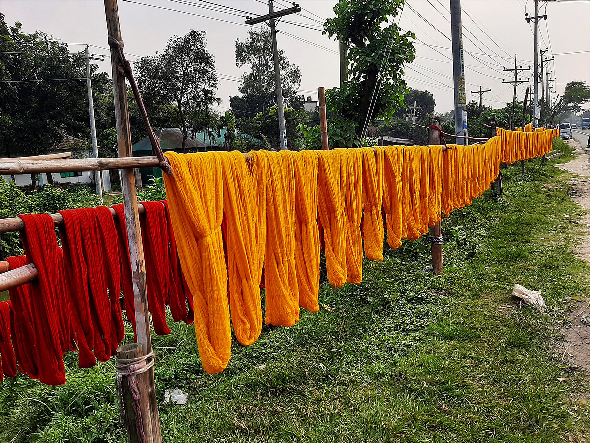 Workers have spread yarn to dry beside the highway.