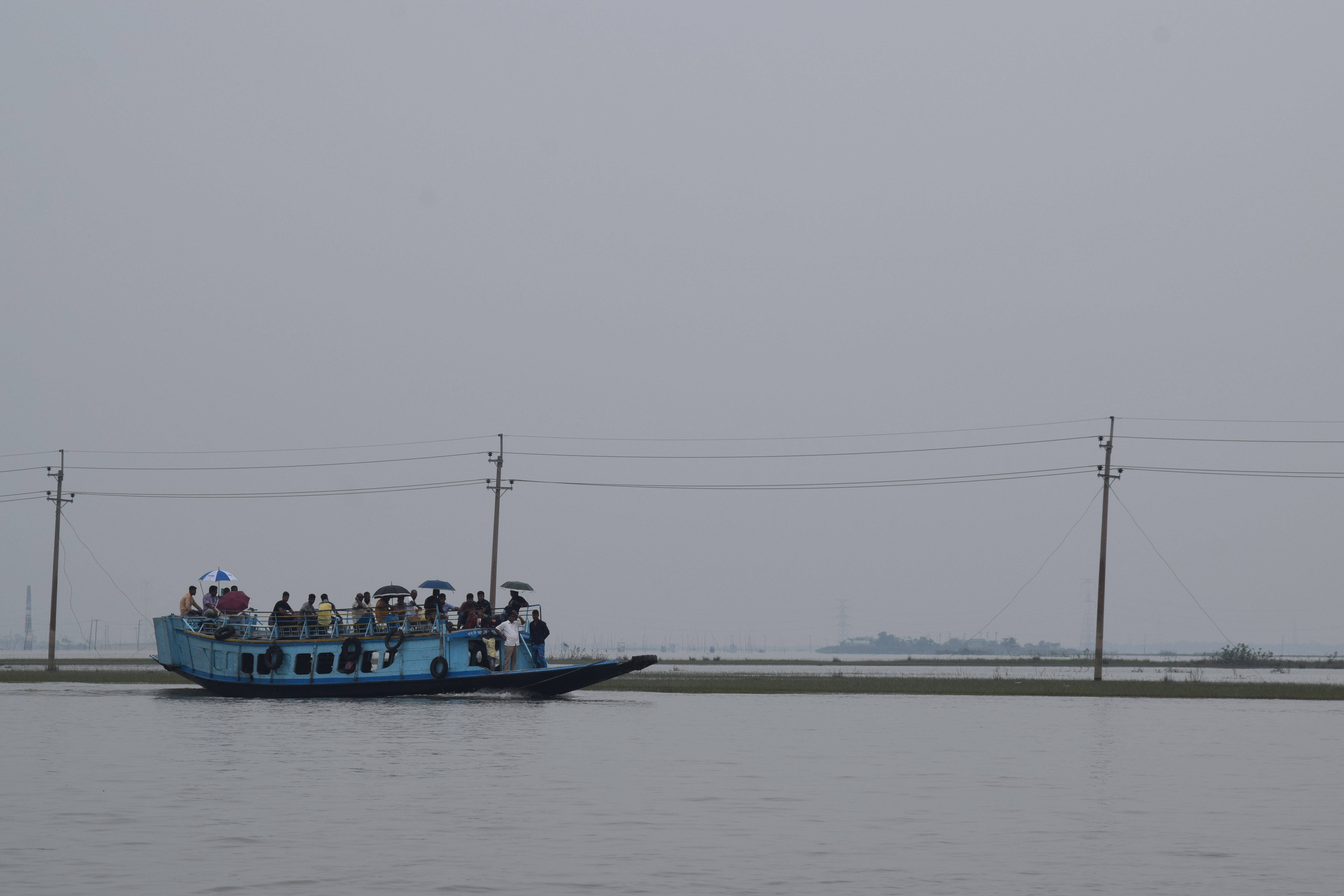 ২০২২ সালের জুলাইয়ে কিশোরগঞ্জের মিঠামইন উপজেলায় একটি সড়কের পাশে পানিতে ভরা হাওরে যাত্রীবাহী নৌকা। শুষ্ক মৌসুমে এই জমিতেই বোরো চাষ হয়। ছবি: Frameofashik / উইকিমিডিয়া কমন্স (সিসি বাই-এসএ ৪.০)